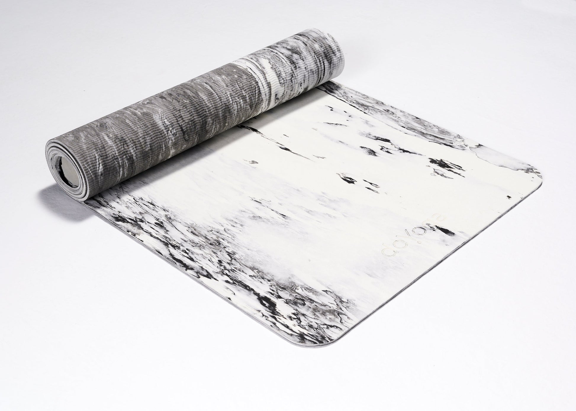 Zrolowana do połowy mata do jogi TPE w kolorach biało czarnych na białym tle. Pokazana w ujęciu z boku. 