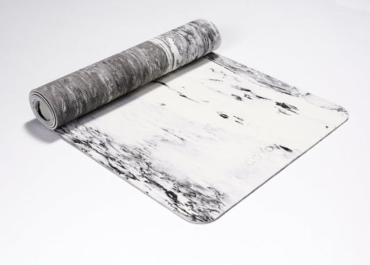 Zrolowana do połowy mata do jogi TPE w kolorach biało czarnych na białym tle. Pokazana w ujęciu z boku. 